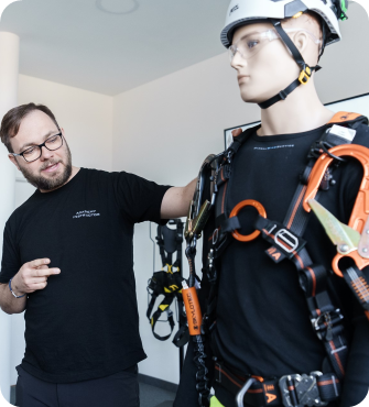 Instructor explaining fall-protection equipment on a training mannequin
